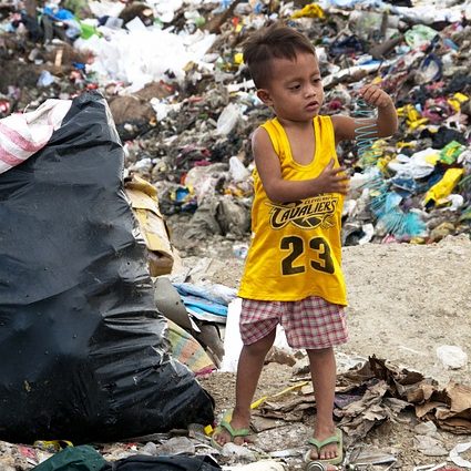 kleiner Junge umgeben von Plastikmüll